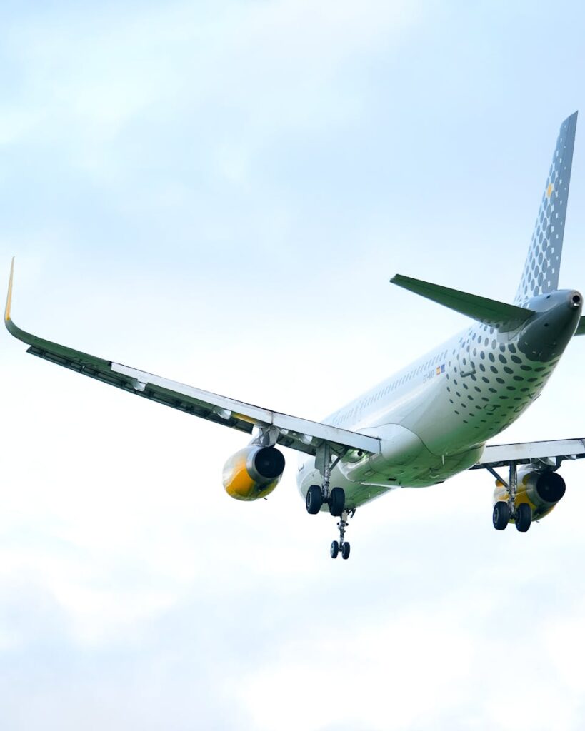 A commercial airplane soaring through a cloudy blue sky, showcasing aviation and travel.