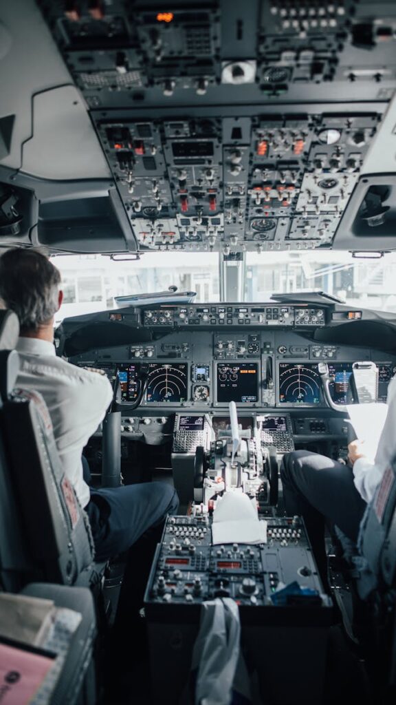 Pilots seated in a commercial jet cockpit with a view of control panels