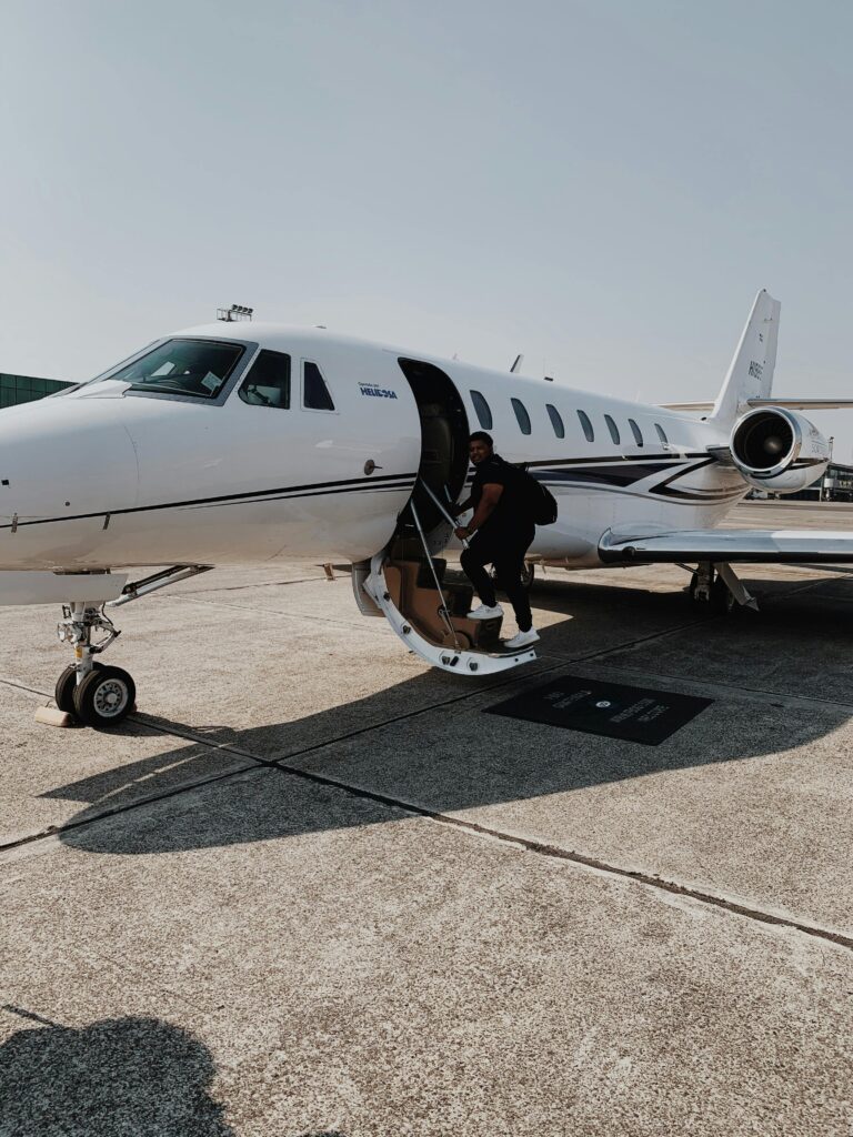 A passenger boards a private jet at a sunlit airport runway, capturing luxury travel.