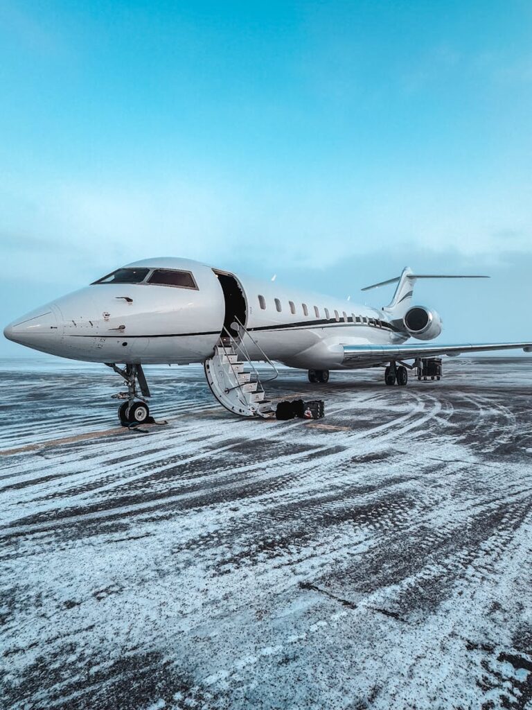 Private jet parked on a snowy airport runway during winter, clear sky.