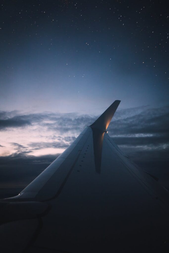 A serene view of the airplane wing against a twilight sky full of stars.