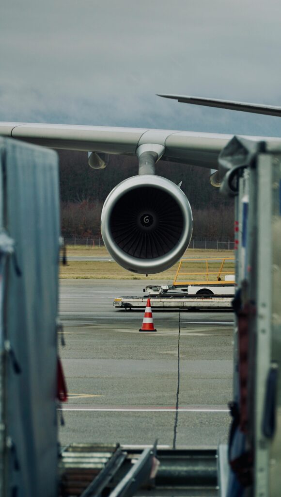 Close-up of an airplane jet engine on the runway at Geneva Airport, overcast day.