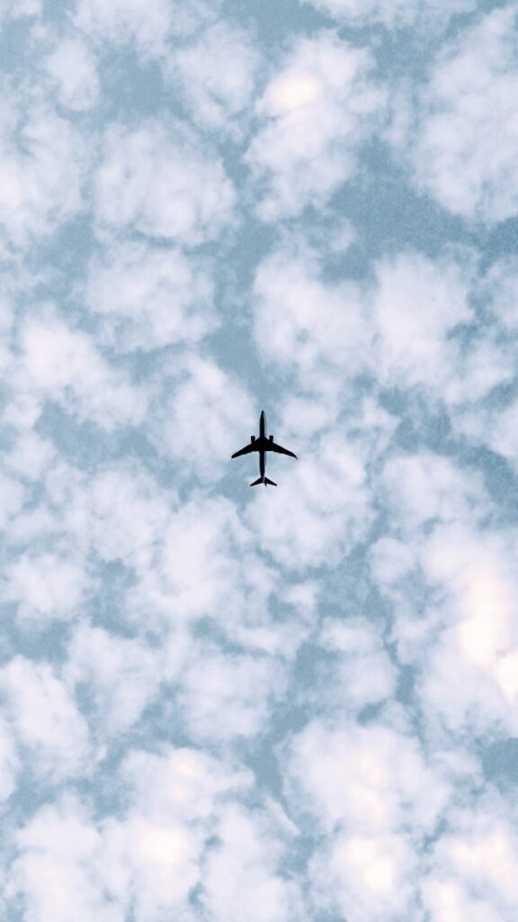 an airplane flying through a cloudy blue sky